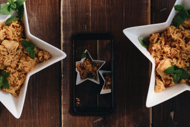 Star-shaped bowls filled with chicken rice and herbs, captured with a top view and a smartphone reflection.