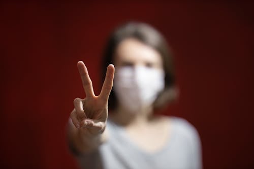 Selective Focus Photo of a Person's Hand Doing the Peace Sign