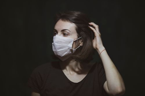 Free Portrait of a woman wearing a face mask, highlighting pandemic safety measures. Stock Photo