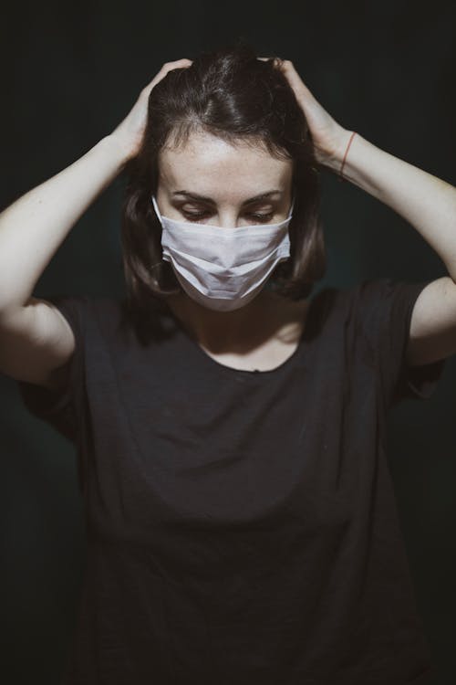 Free Woman in Black Crew Neck T-shirt Covering Her Face With White Face Mask Stock Photo