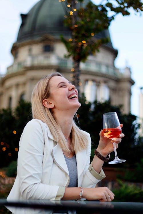 Laughing woman drinking wine in street restaurant
