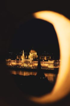 夜晚，布达佩斯匈牙利议会大厦的景色透过圆形框架，被美丽地照亮