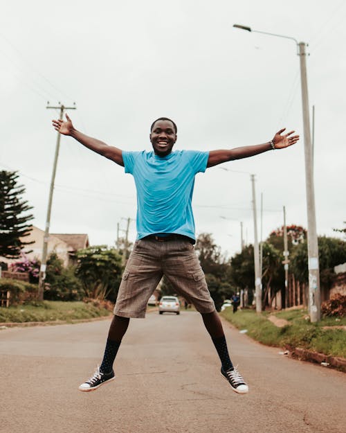 Black happy man jumping on street