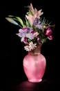 黑色背景上，粉红色花瓶中盛开着充满活力的花朵，排列美丽
