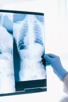 Medical professional in blue gloves analyzing a chest X-ray image indoors.