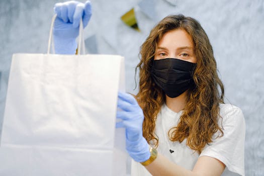 Young woman wearing mask and gloves, holding a paper bag indoors, emphasizing safe shopping practices.