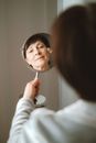一名白人妇女在室内对着镜子微笑着化妆