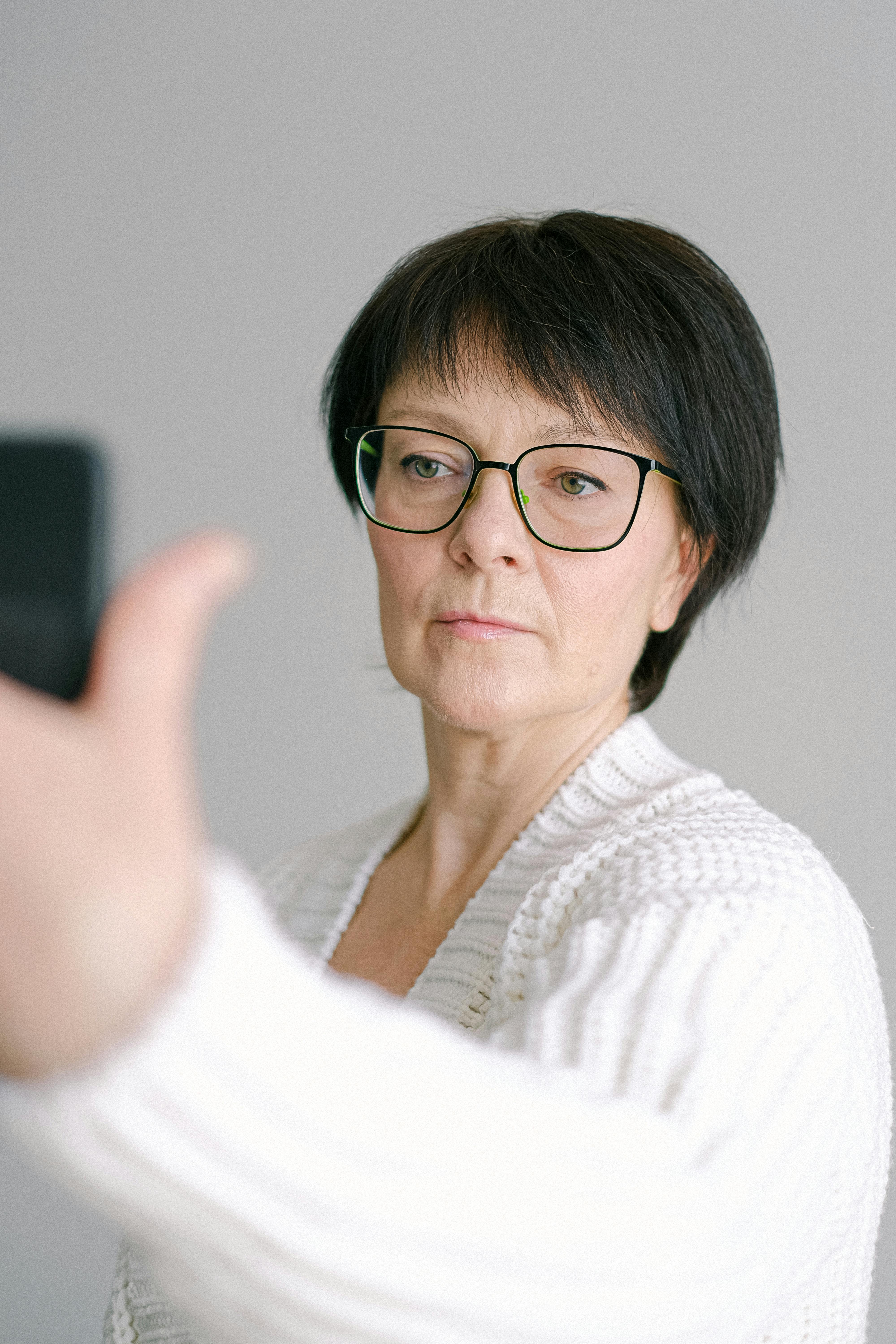 Senior woman with glasses takes a selfie indoors, capturing a candid moment.