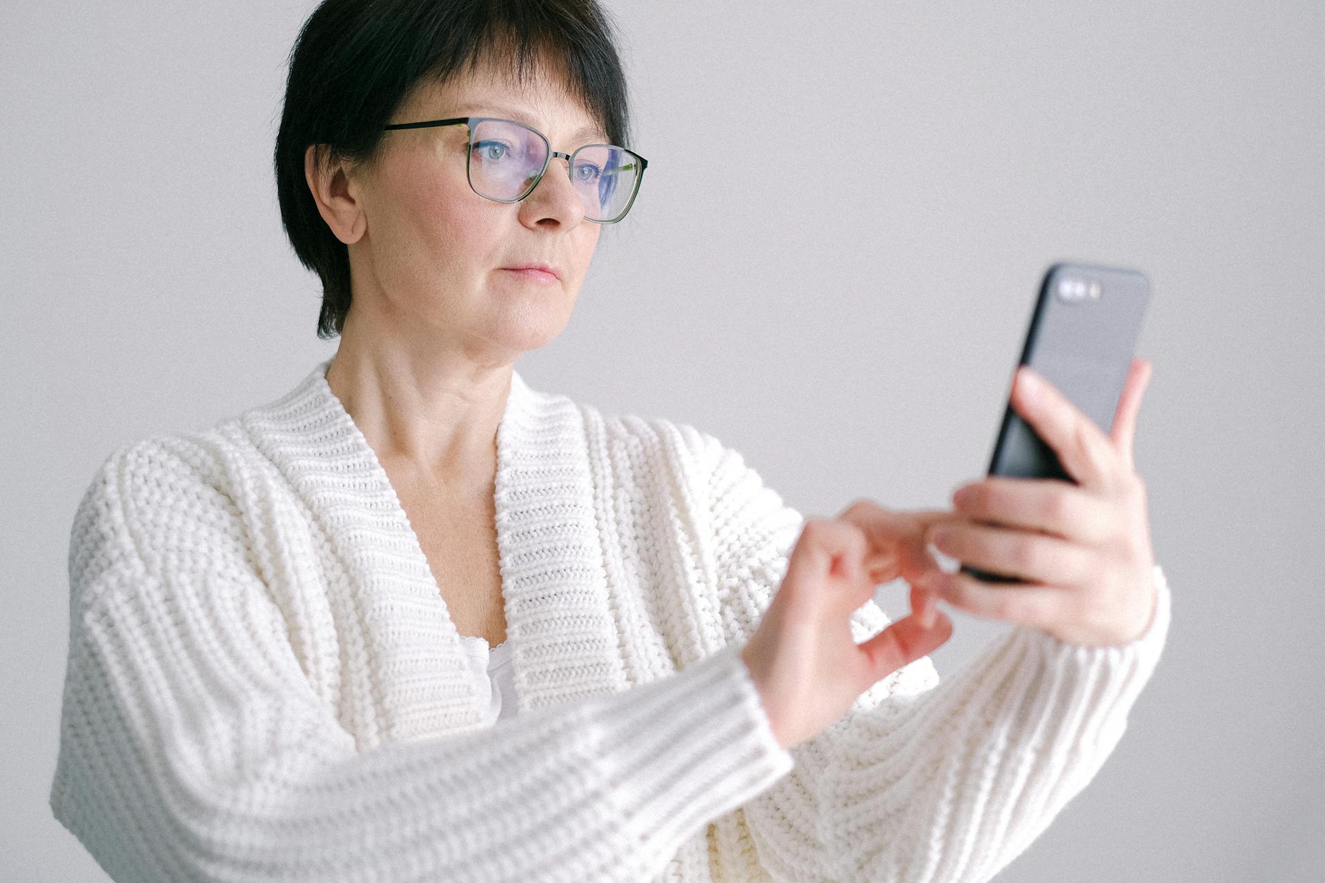 Vue rapprochée d'une femme en cardigan blanc utilisant un smartphone