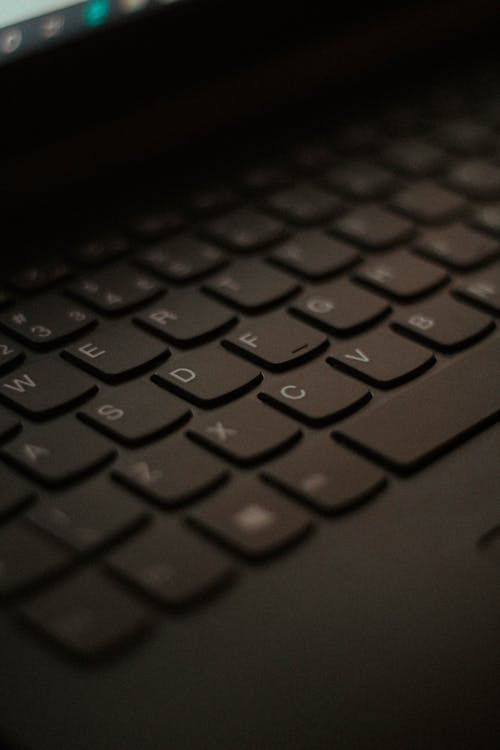 From above of black keypad of modern laptop with buttons placed at workplace