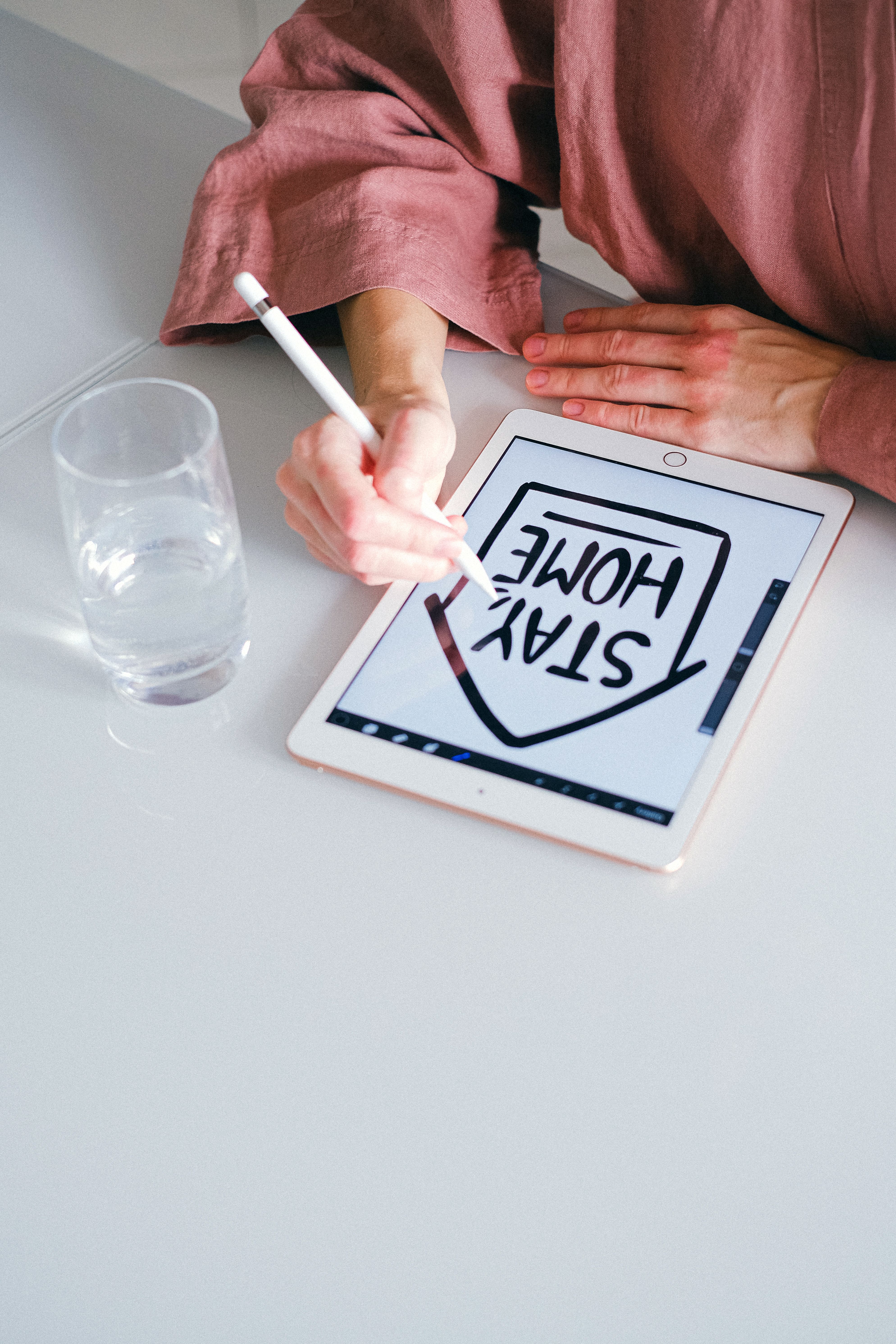 Person using a stylus pen for digital drawing on tablet with 'Stay Home' design.