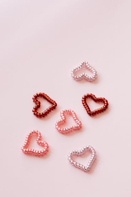 Colorful coil hearts on pale pink background · Free Stock Photo
