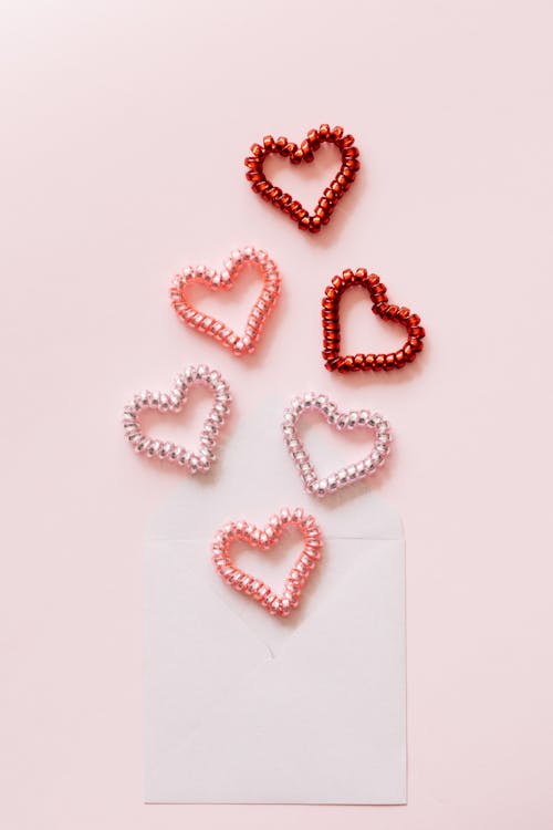 Composition of decorative coil hearts and open envelope