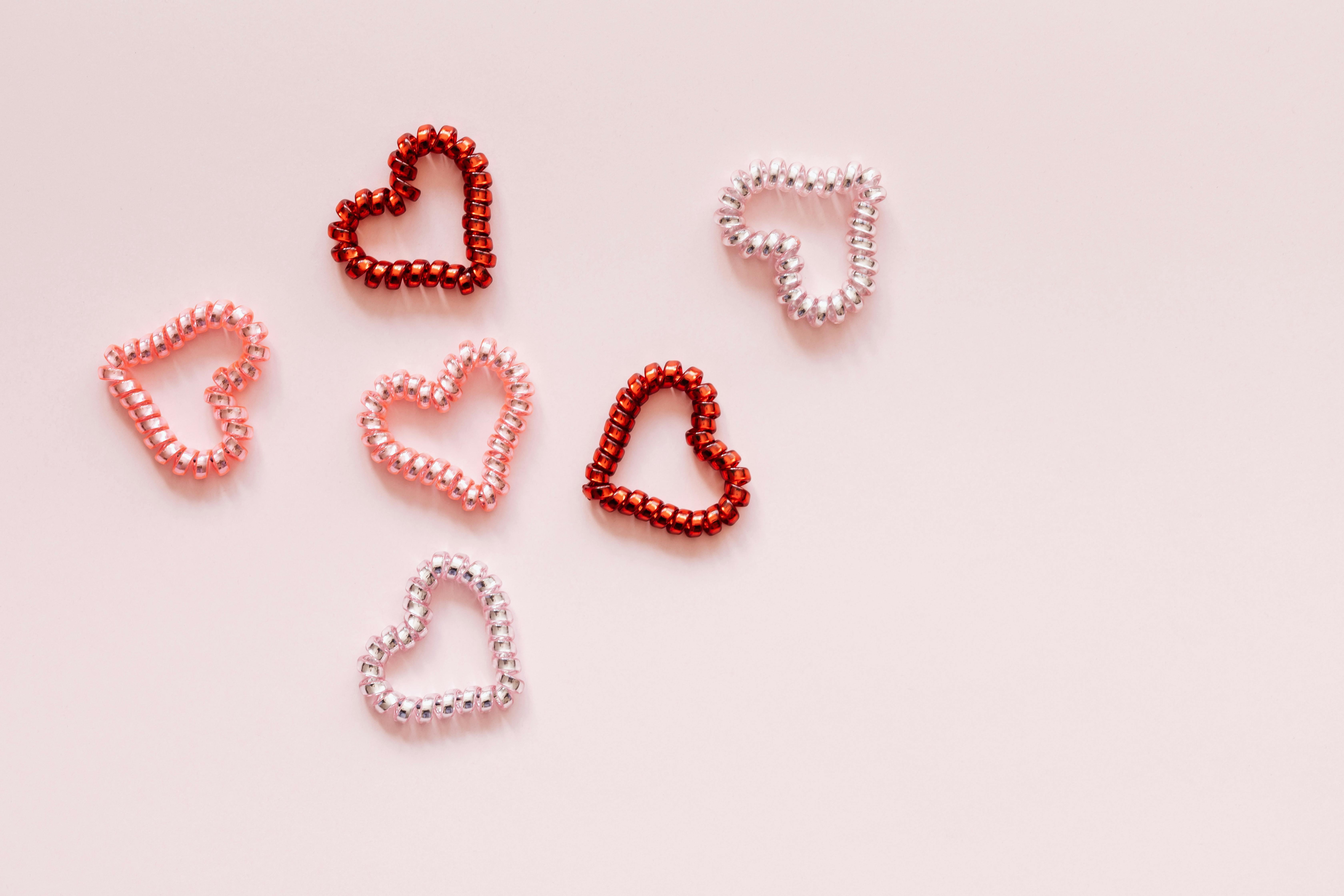 multicolored decorative hair ties in heart shape on pink background