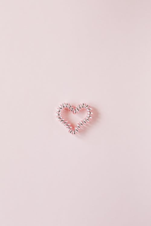 Free Decorative heart of elastic coil on pink background Stock Photo