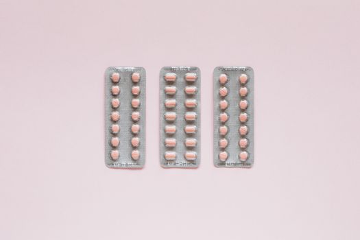 在柔和的粉色背景上，排列着包装好的药丸，这是顶视图