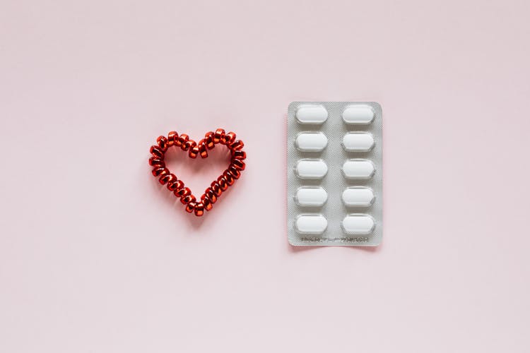 Composition Of Heart And Pills On Pink Background