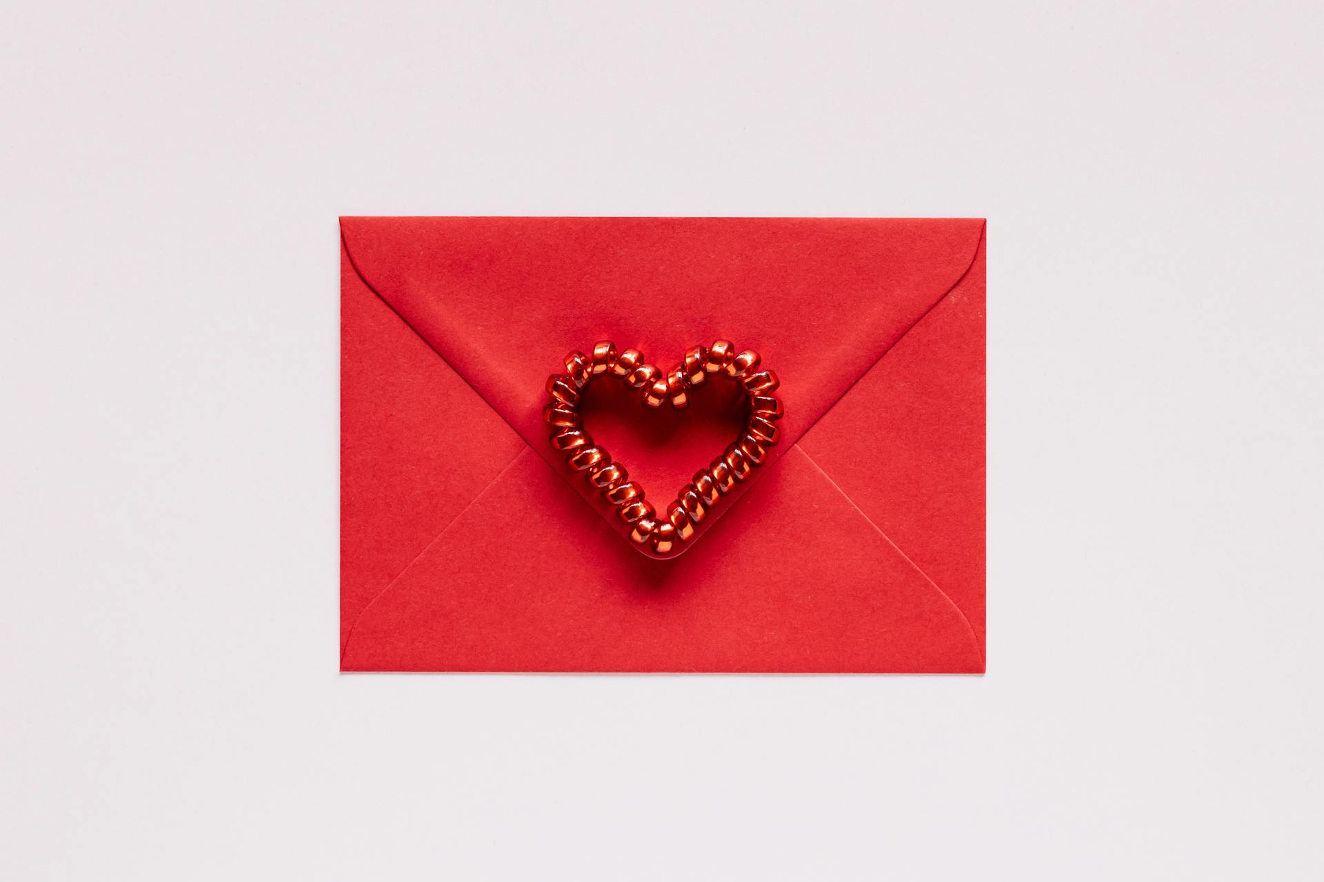 Colorful gift envelope with heart on pink background