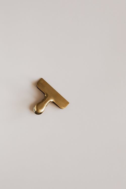 Top view of golden paper clip placed on beige surface