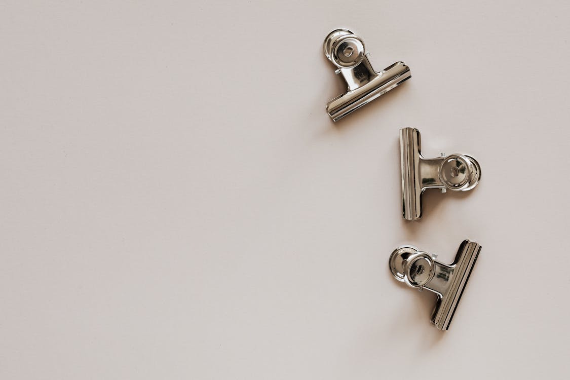 Set of metal clips on light grey background · Free Stock Photo