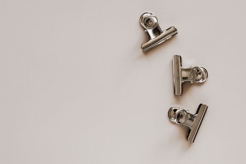 Free From above of identical metallic clips made of solid material with smooth surface on beige background Stock Photo