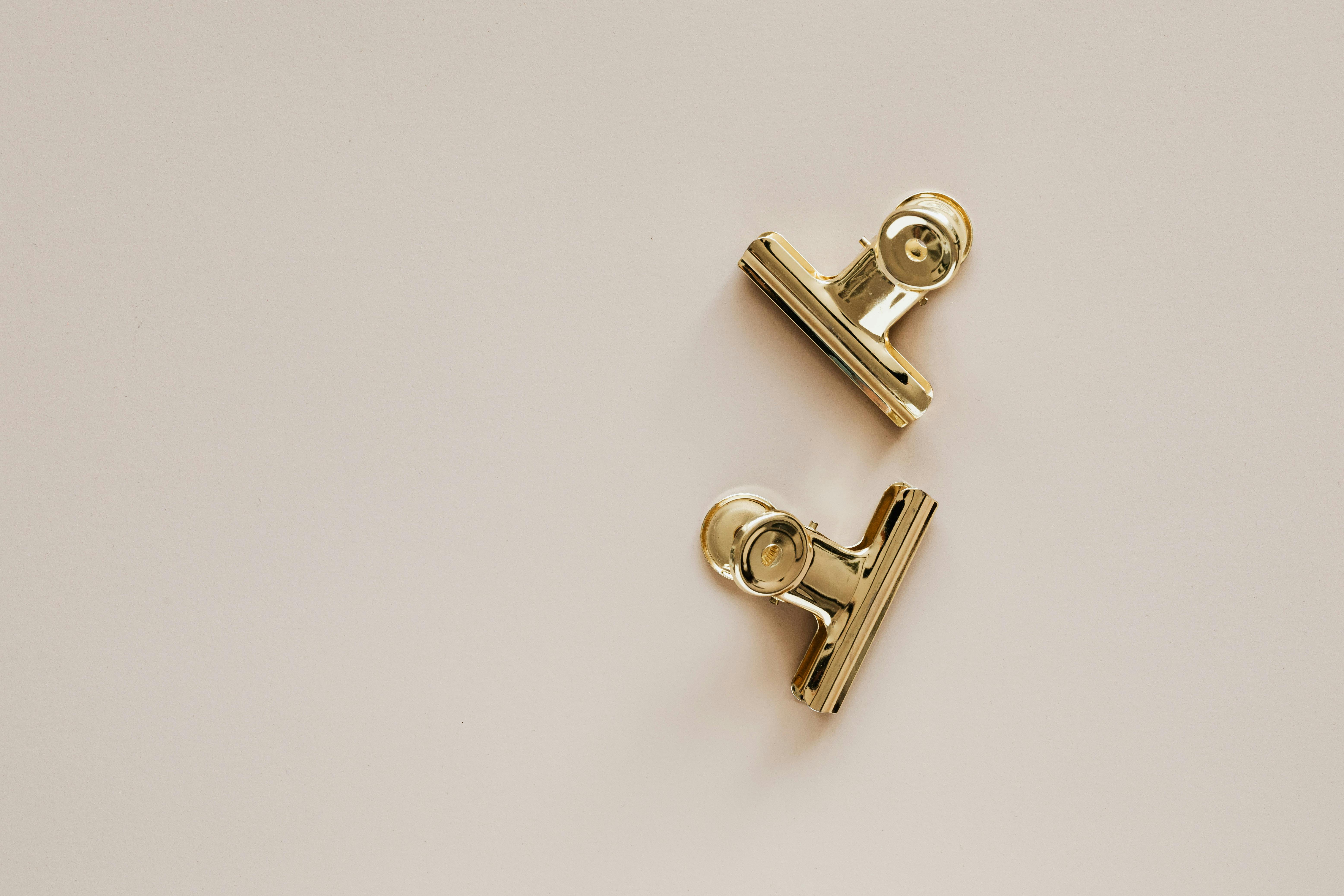 golden metal clips on beige background