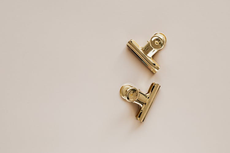 Golden Metal Clips On Beige Background