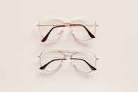 From above of fashion spectacles for vision with golden and silver metal shells placed on white table