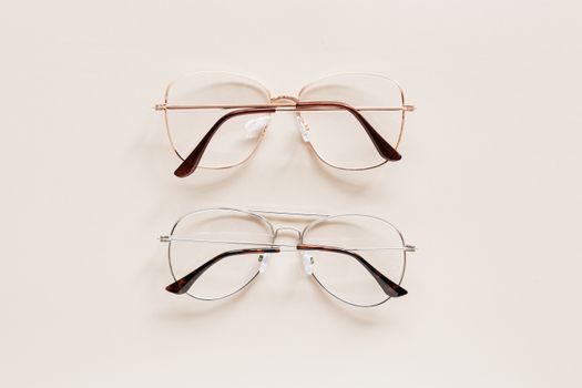 From above of fashion spectacles for vision with golden and silver metal shells placed on white table