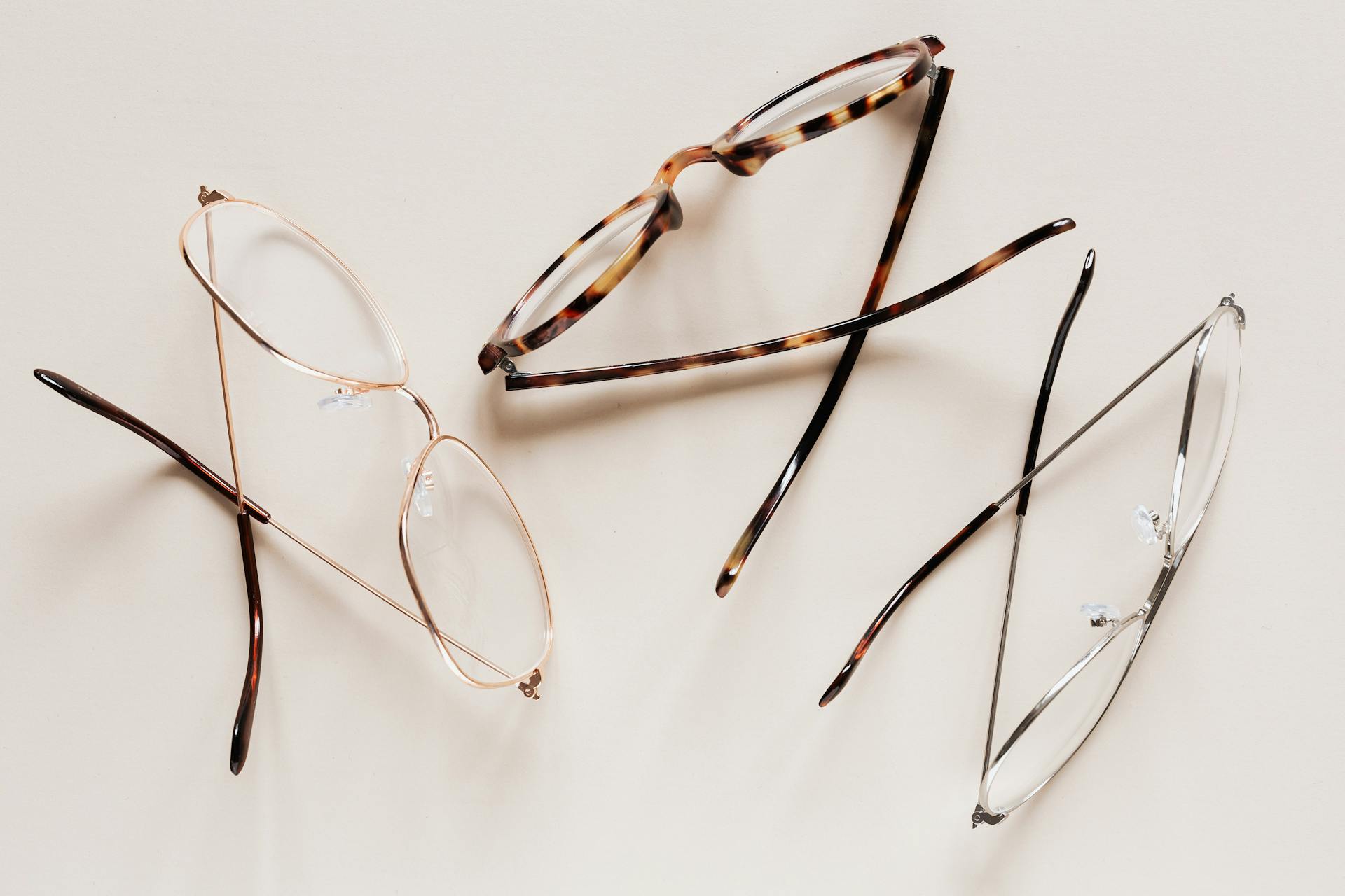 From above of fashion glasses with optical lenses for vision correction in metal shells together with pair in plastic tortoise shell placed on white table