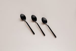 Set of shiny black spoons on gray table