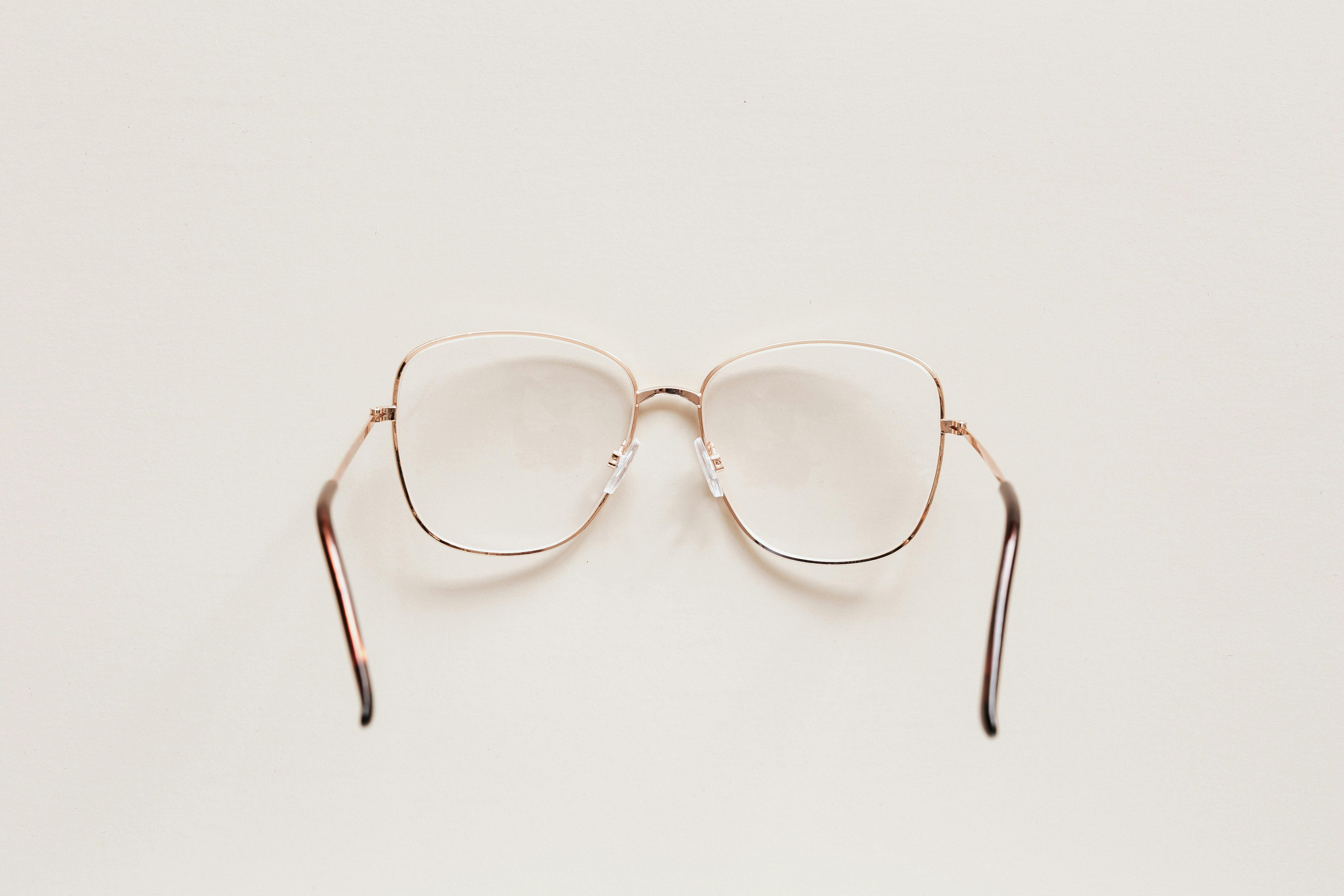 Top view of fashion spectacles with transparent optical lenses in golden metal shell placed on white table