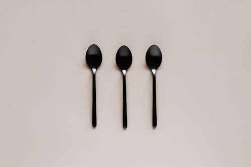 Set of black teaspoons on beige surface