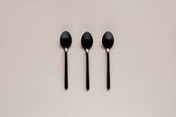 Set of black teaspoons on beige surface