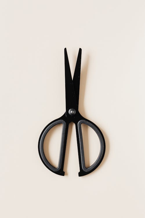 Free Top view of simple black scissors placed vertical on beige surface Stock Photo