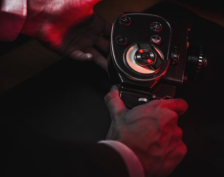 Close-up of hands holding a vintage camera with red ambient lighting.