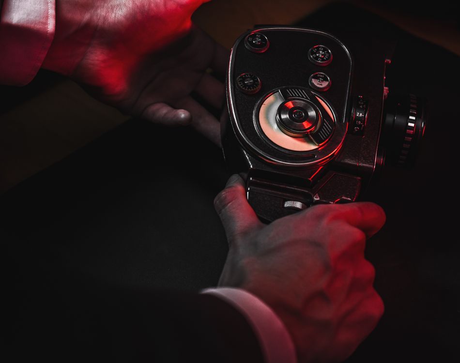 Free Close-up of hands holding a vintage camera with red ambient lighting. Stock Photo