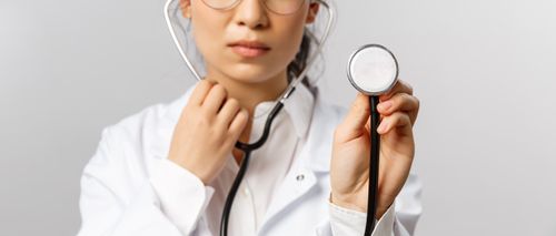 Free Close-up of a female doctor in a white lab coat, holding a stethoscope. Stock Photo