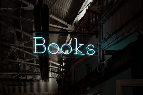 Free A glowing neon 'Books' sign inside a dimly lit bookstore in New York. Stock Photo