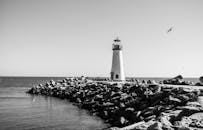 一张黑白照片静谧无声，灯塔被岩石与海洋环绕其中