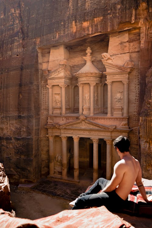 Topless Man Sitting on a Cliff Across the Famous Petra