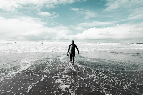 Free Back View of Man Holding a Surfboard While Walking to the Sea Stock Photo