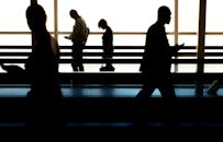 在明亮的背景下，剪影般的人们在室内行走，传达出动感和匿名性