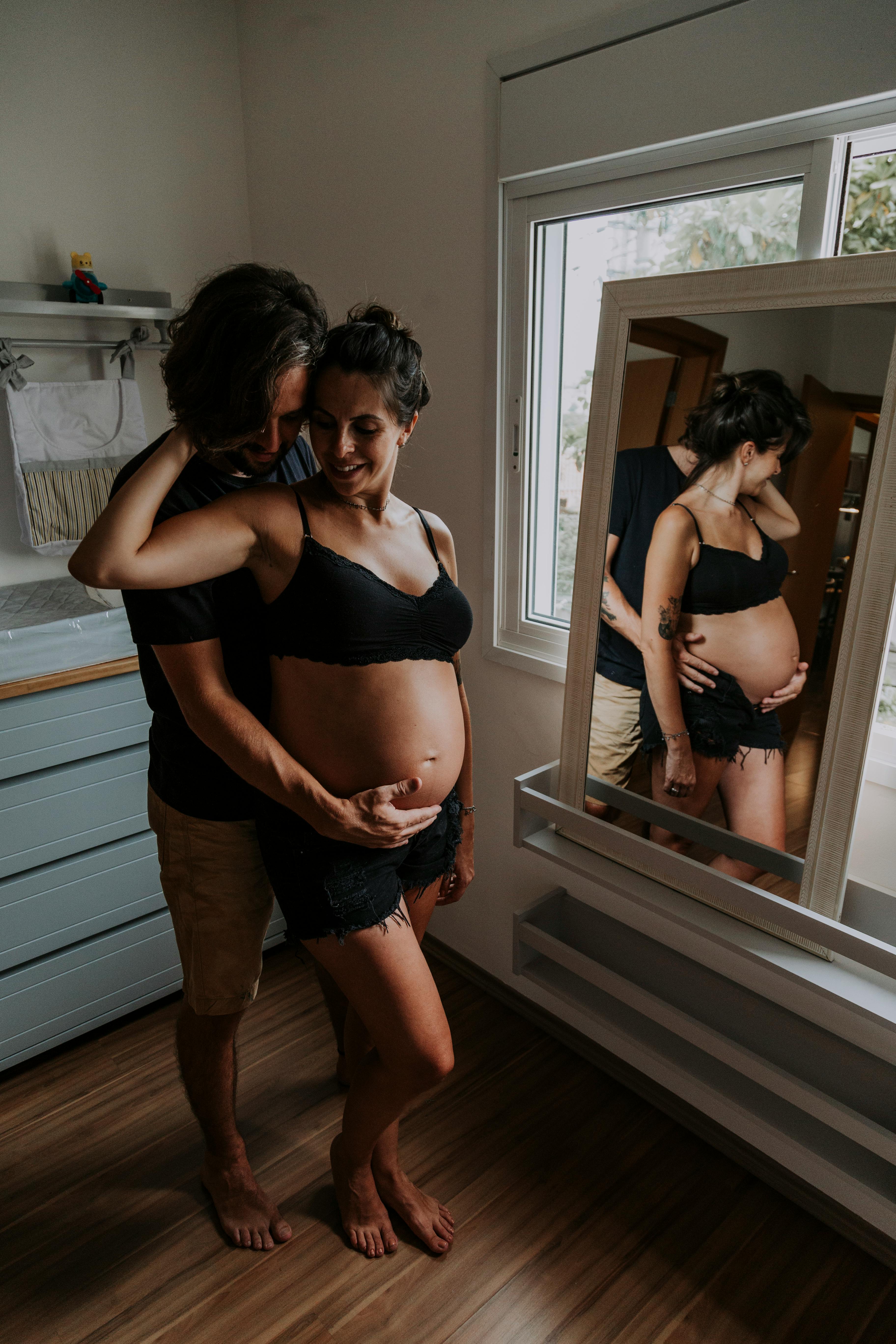 A loving couple embracing during pregnancy in a cozy indoor setting.