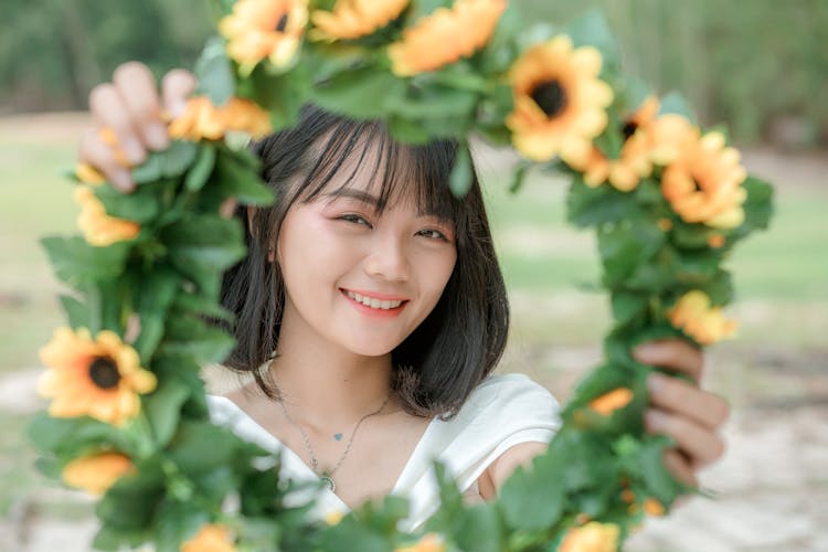 Glad Asian Woman Showing Bright Flower Wreath