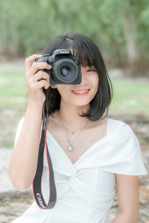 Stylish smiling ethnic woman taking photo with camera