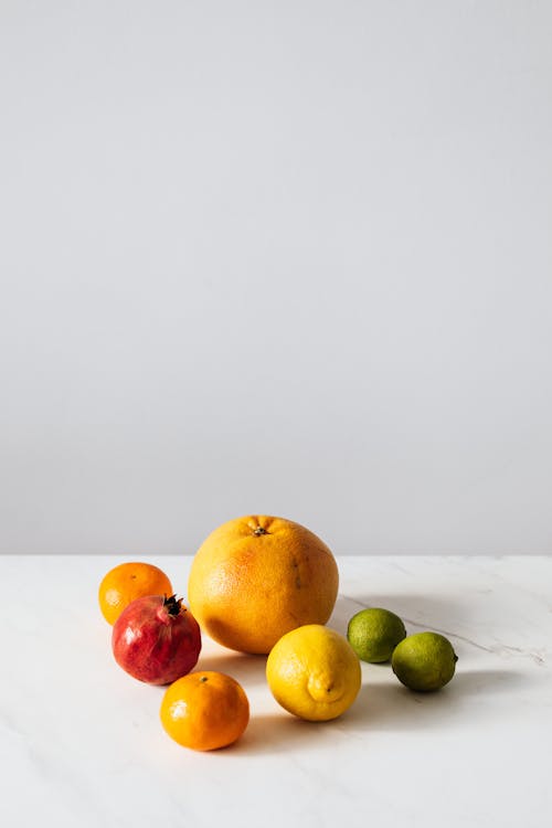 Assorted ripe fruits placed on white table on gray background