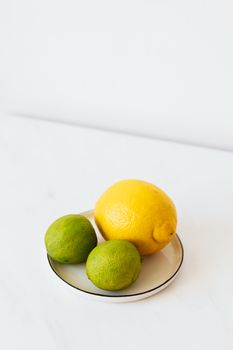 白色盘子里放着明亮的柠檬和酸橙，看起来清新自然