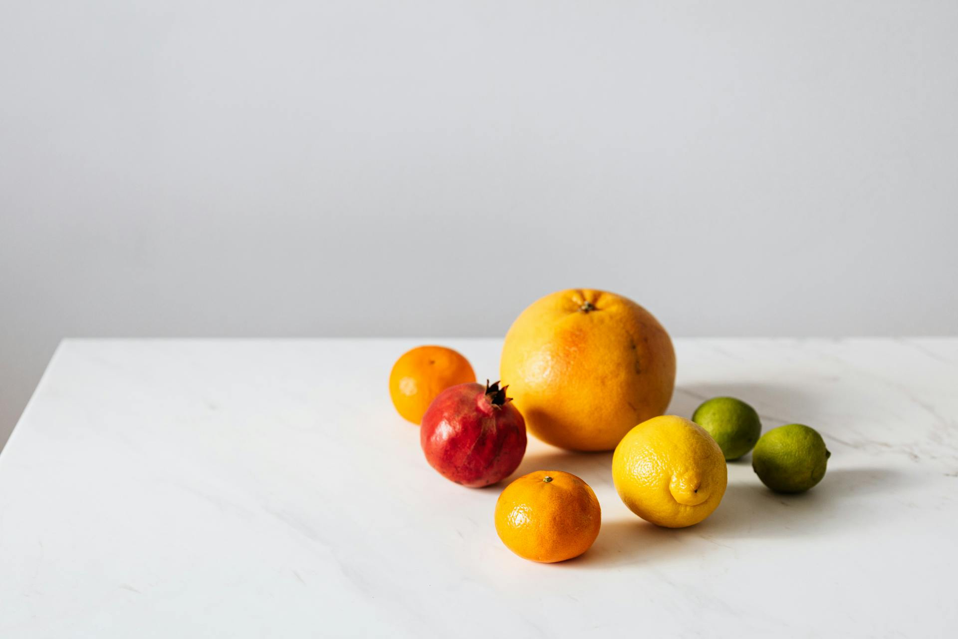 A fresh selection of citrus and exotic fruits on a white marble surface offering healthy vibes.