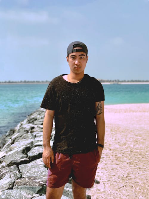 Man in Black Shirt and Red Shorts Standing near the Sea
